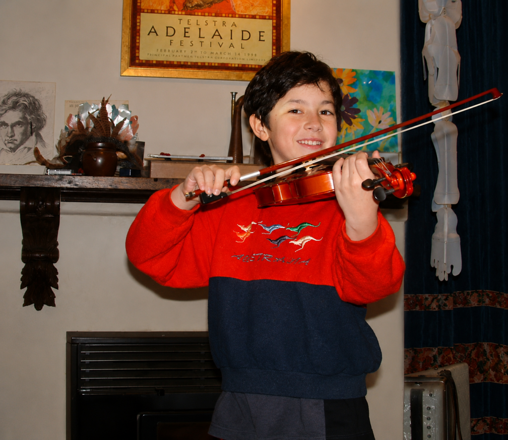 Sami playing violin in front of poster